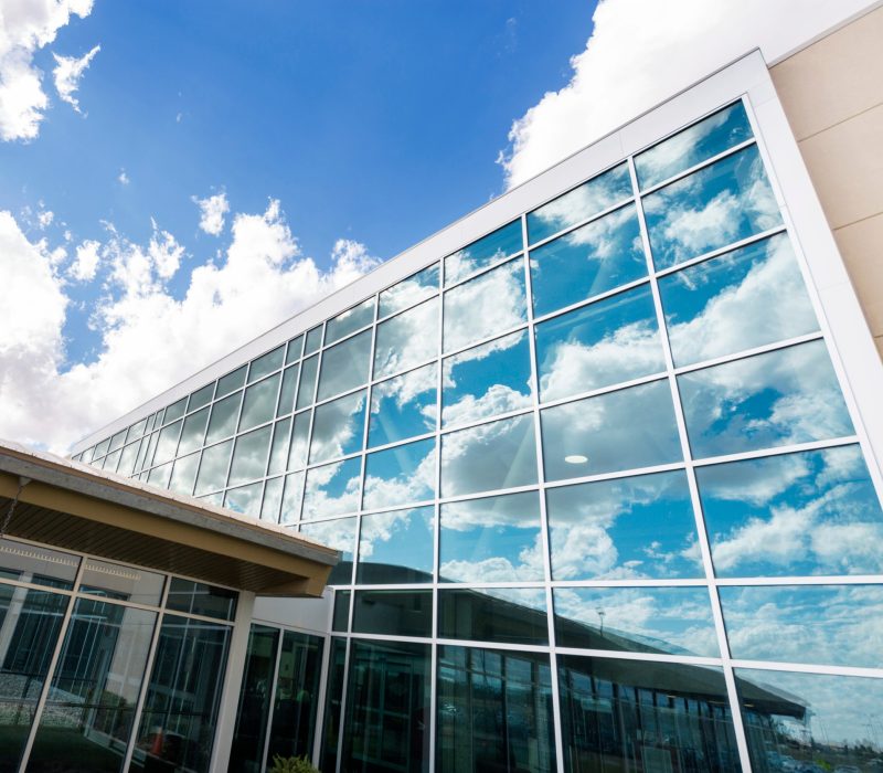 Low angle view of modern hospital building with reflection of clouds on glass windows